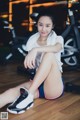 A woman sitting on the floor in a gym.