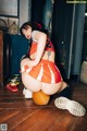 A woman in an orange and white cheerleader outfit crouching on the floor.