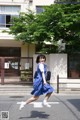 A woman in a blue dress is crossing the street.